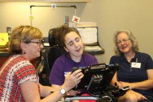 Disabled woman using tablet with the help of staff members