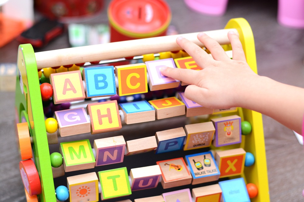 Child's hand playing with letter blocks