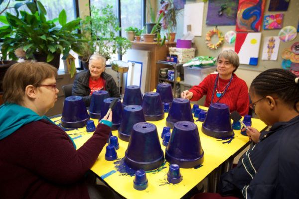 Group of older disabled women painting clay flower pots