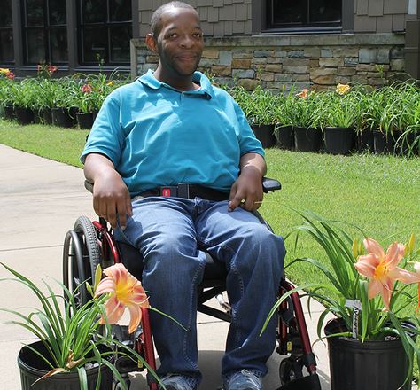Man in wheel chair next to flower pots