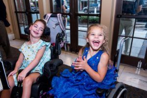 Two young girls in wheel chairs laughing