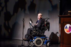 Man in wheelchair on stage speaking at Journey of Hope event