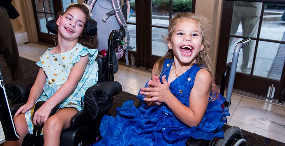 Two girls in wheel chairs laughing at Journey of Hope event