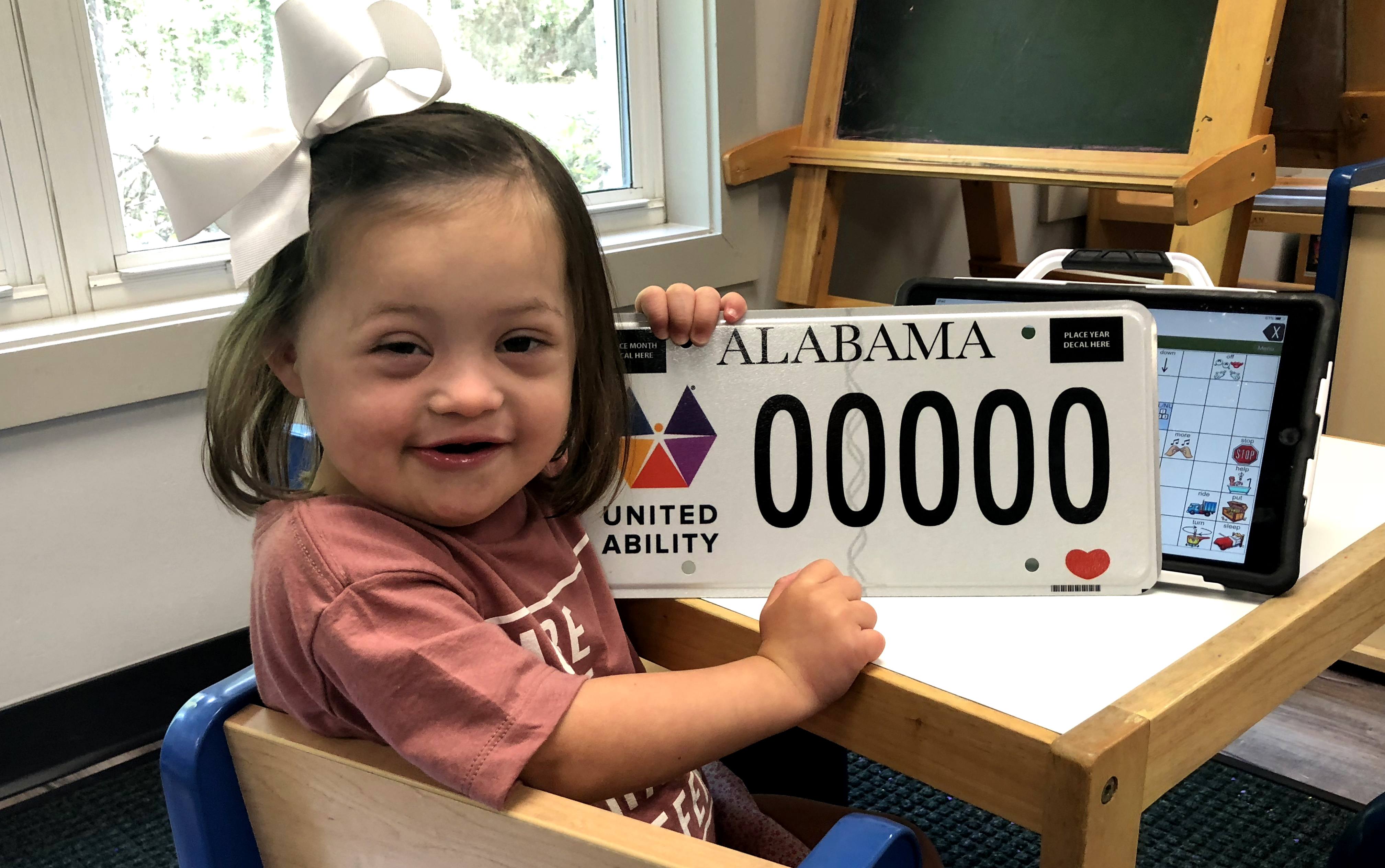 young girl holding united ability car tag