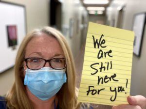 woman holding sign which reads we are still here for you